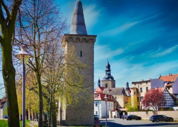 Hettstedt - Stadtmauer Turm "Kunstzuckerhut" neben der Wipper und blühenden Bäumen mit Gebäuden im Hintergrund