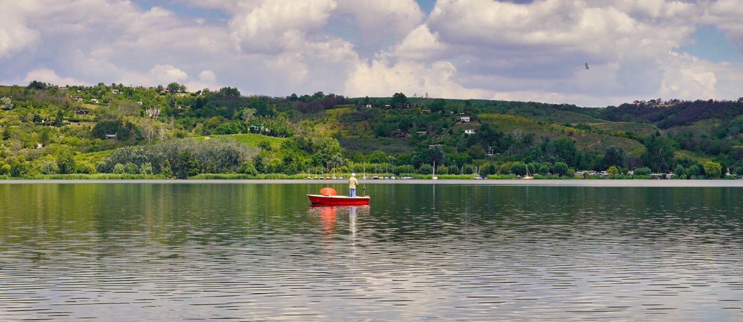 Mansfelder Land - kleines Boot auf dem Süßen See mit Weinbergen im Hintergrund