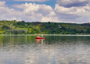 Mansfelder Land - kleines Boot auf dem Süßen See mit Weinbergen im Hintergrund