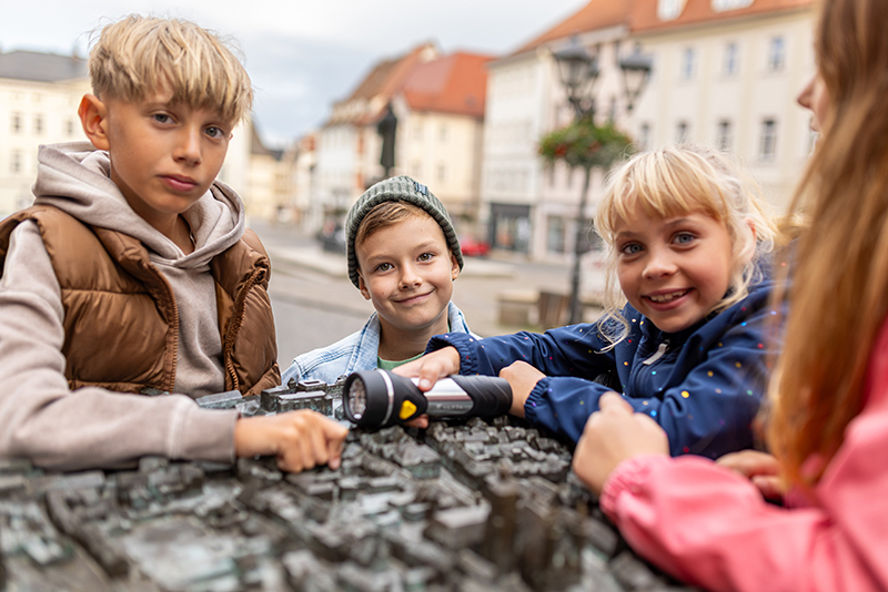Vier Kinder stehen um das Stadtmodell von Lutherstadt Eisleben auf dem Marktplatz